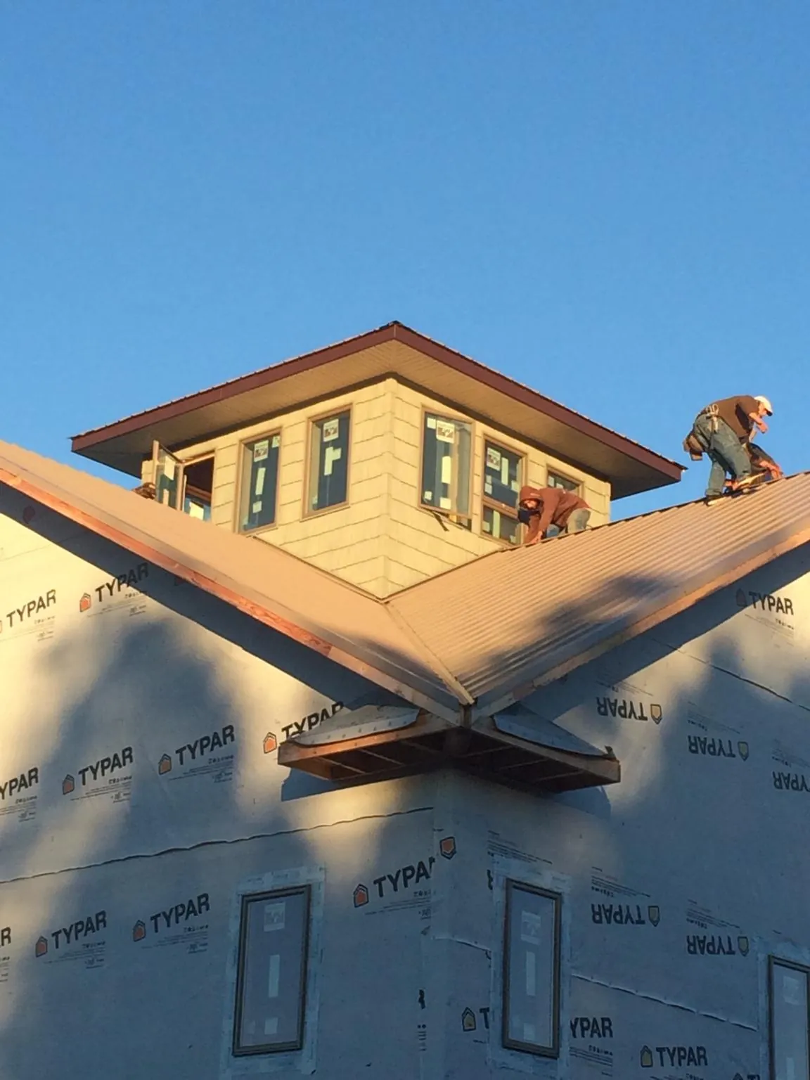 Roofers working around a rooftop cupola on a new metal roof at sunset — Roof Waterproofing in Granby by Roofing Brothers
